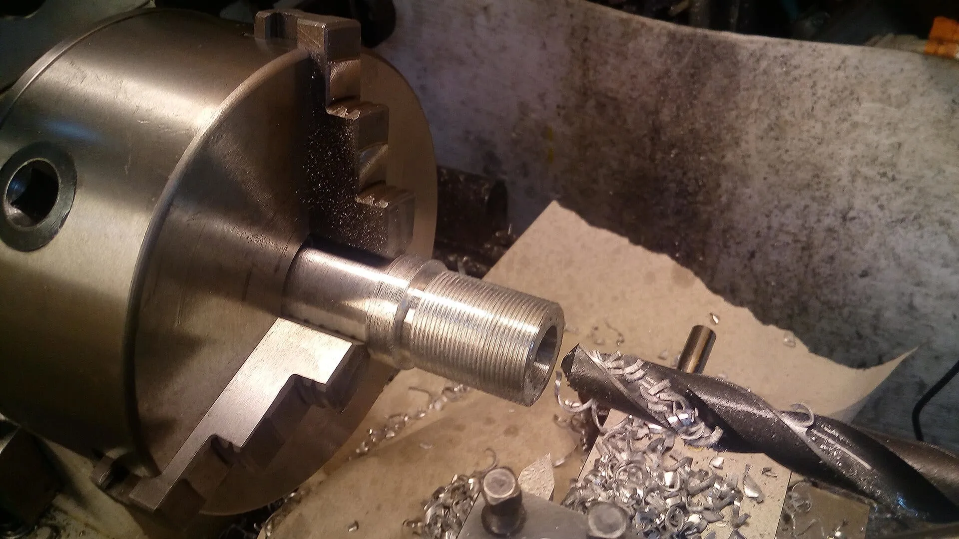Machined component in a lathe chuck, swarf on the bed