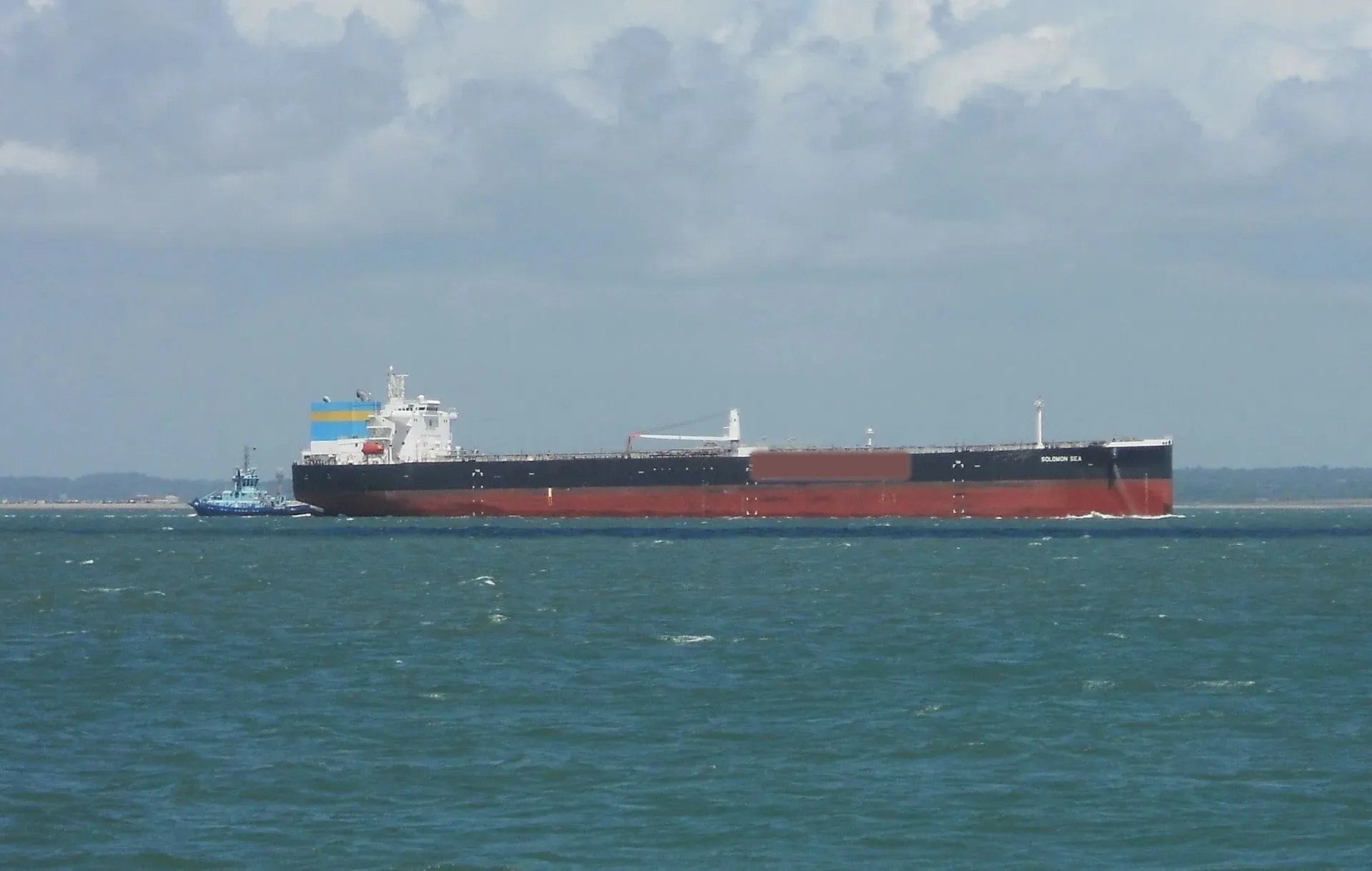 Laden tanker underway with tug escort
